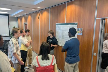 Lucia Curran-Lane, Michael Gyampo, and Finlay Savoir presenting their summer research poster